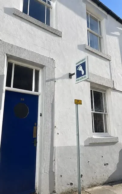The white terraced frontage on Battle Hill with a blue door and a blue chiropodist and podiatrist sign.